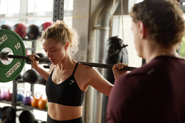 Athlete lifting a barbell with the coach